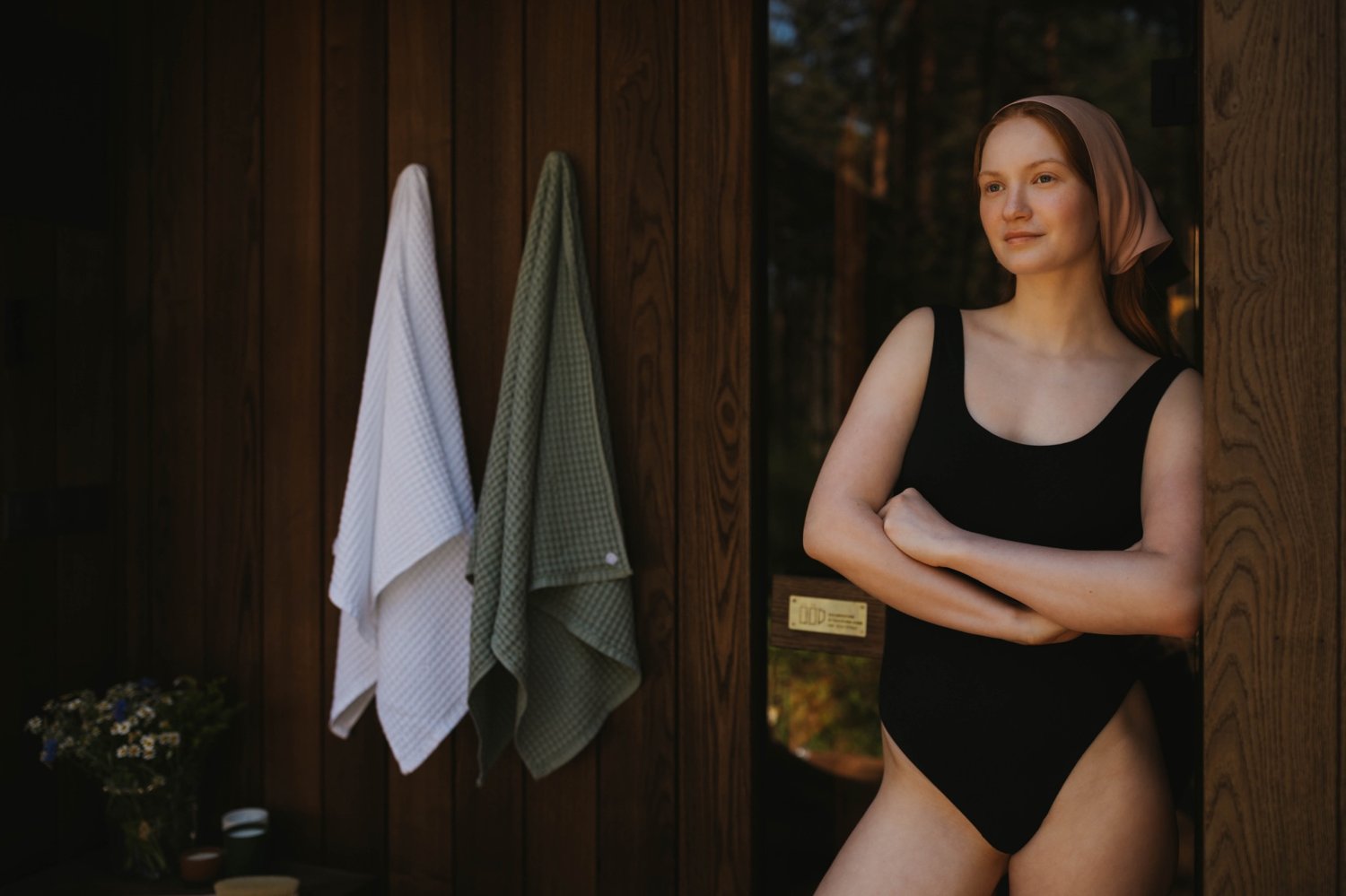 Woman wearing plant-based swimwear beside a sauna